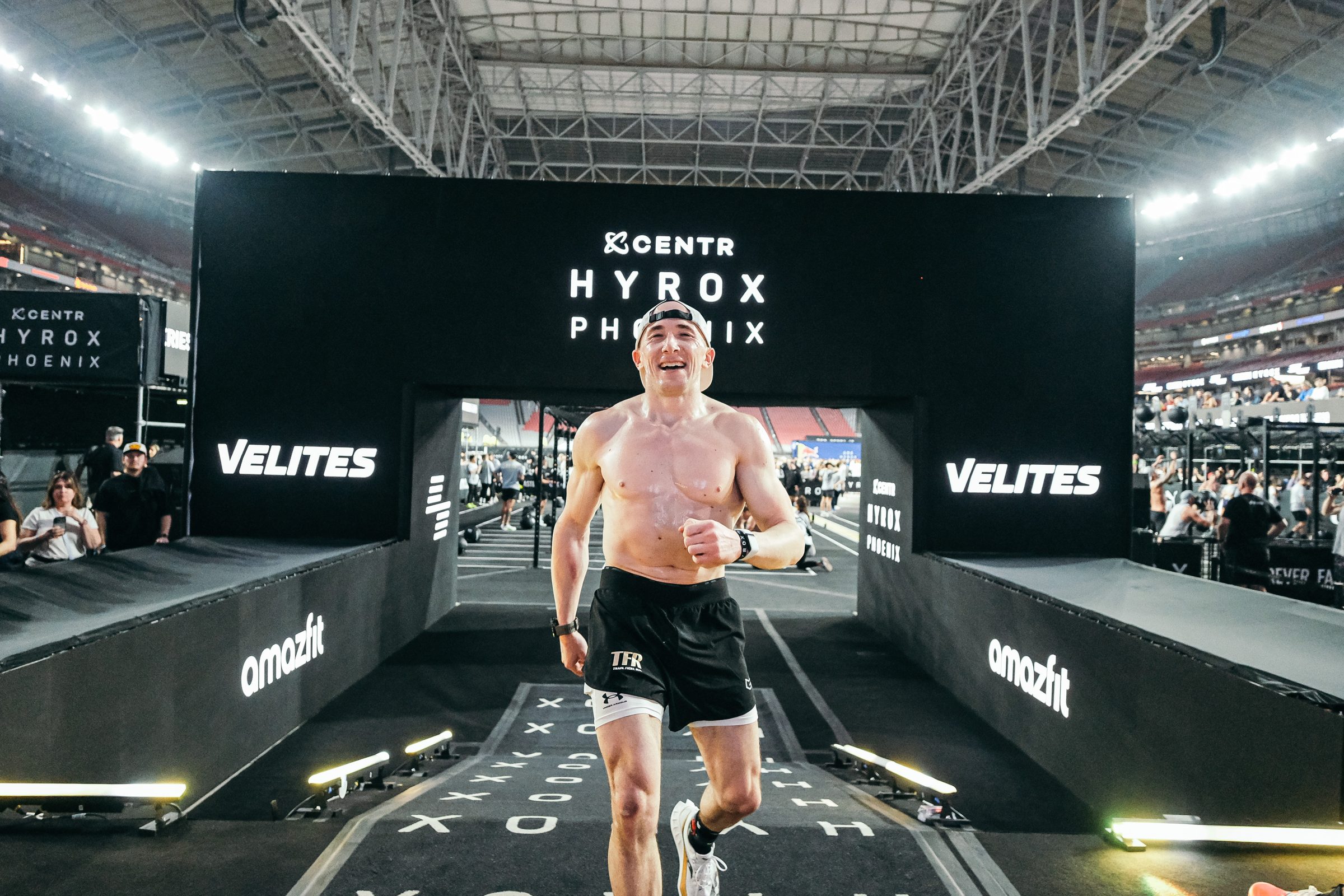 Adam running through the finish arch at HYROX Phoenix, State Farm Stadium